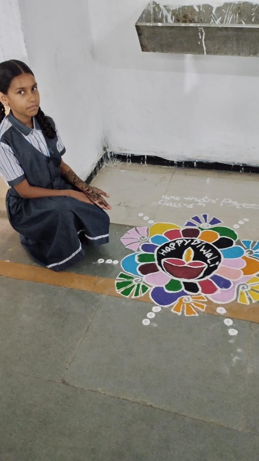 Student with a Happy Diwali rangoli